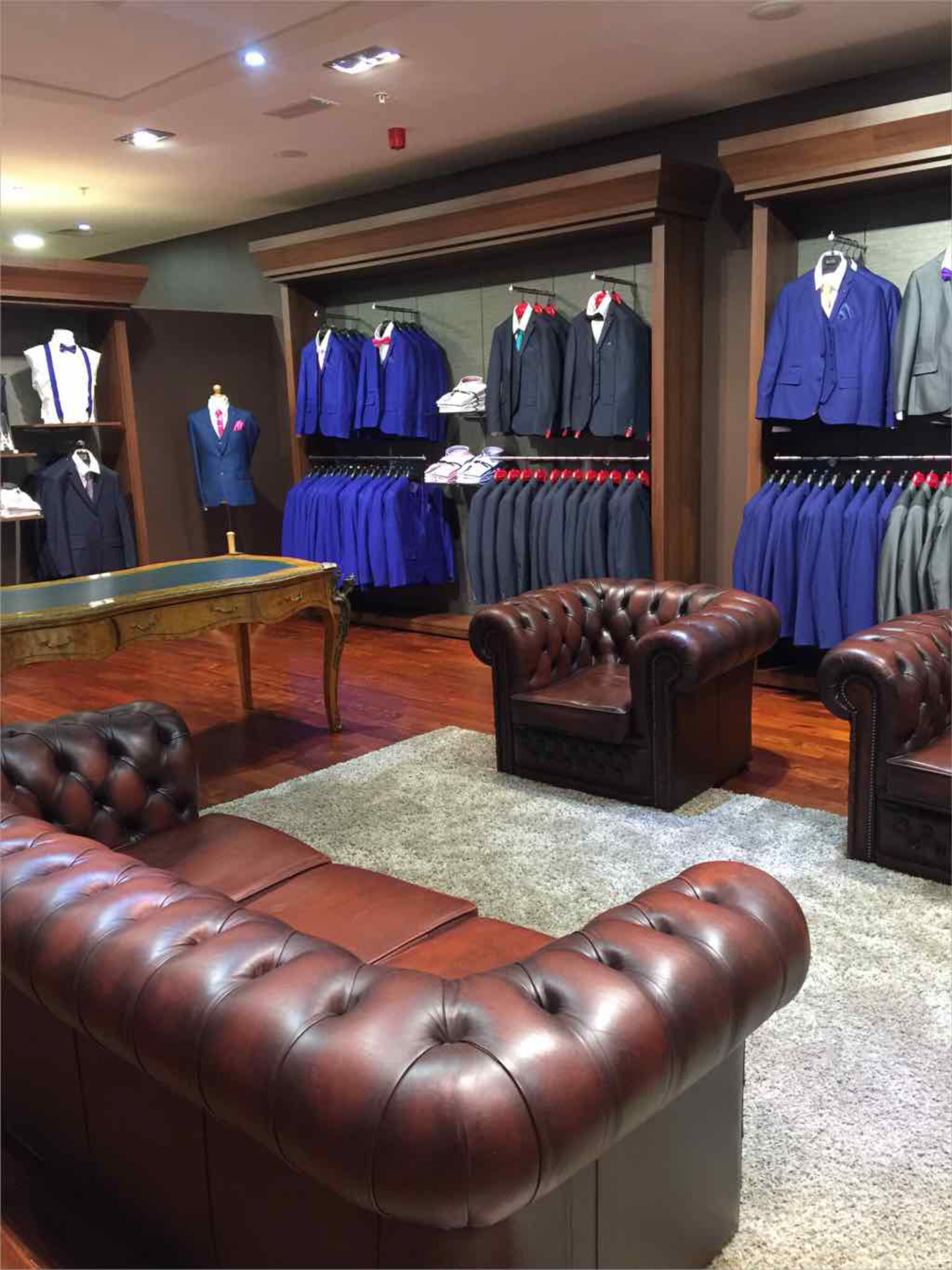 Menswear suit department with comfortable seating area and merchandising systems.